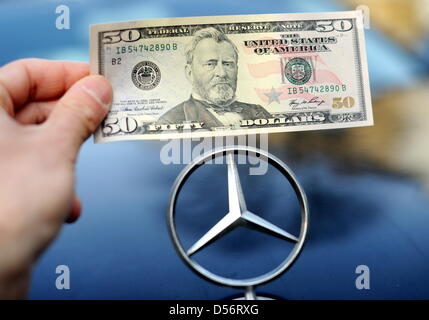 ILLUSTRATION -  A Dollar bill is pictured behind a Mercedes star in Hamburg, Germany, 24 March 2010. After years of investigation, the US government has accused Daimler AG of the payment of bribes. According to the US Justice Department, Daimler AG violated US bribe laws in business dealing with 22 countries over ten years to get lucrative orders. Photo: MAURIZIO GAMBARINI Stock Photo