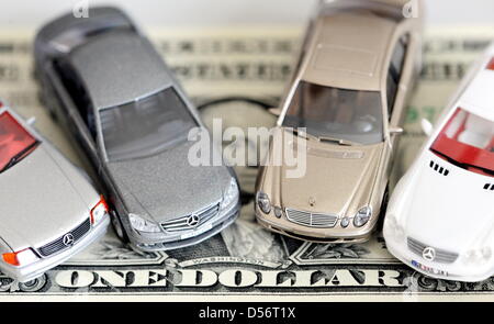 ILLUSTRATION - Mercedes models stand on a Dollar bill in Hamburg, Germany, 24 March 2010. After years of investigation, the US government has accused Daimler AG of the payment of bribes. According to the US Justice Department, Daimler AG violated US bribe laws in business dealing with 22 countries over ten years to get lucrative orders. Photo: MAURIZIO GAMBARINI Stock Photo