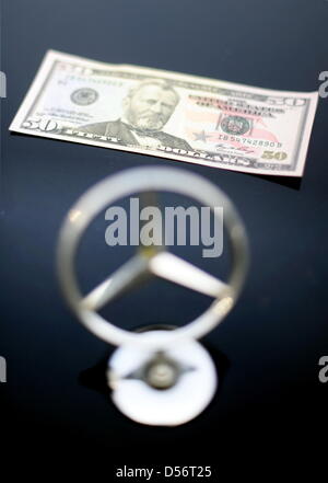 ILLUSTRATION - A Dollar bill placed behind a Mercedes logo in Hamburg, Germany, 24 March 2010. After years of investigation, the US government has now officially sued Daimler AG for the payment of bribes. According to the US Justice Department, Daimler AG violated US bribe laws in business dealing with 22 countries over ten years to get lucrative orders. Photo: MAURIZIO GAMBARINI Stock Photo