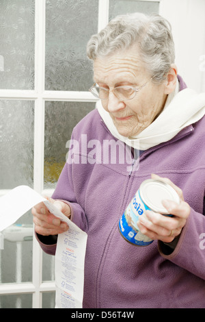 Elderly woman checking prices of shopping looking at till receipt bill Stock Photo