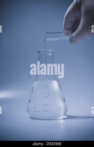 Hispanic scientist pouring liquid into beaker Stock Photo