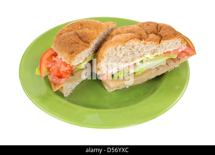 A wheat bulky roll tofu meatless turkey sandwich with lettuce tomatoes and mayonnaise sliced in half on a green plate. Stock Photo
