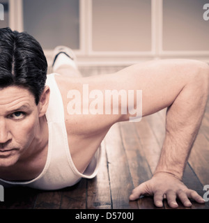 Man doing push ups indoors Stock Photo