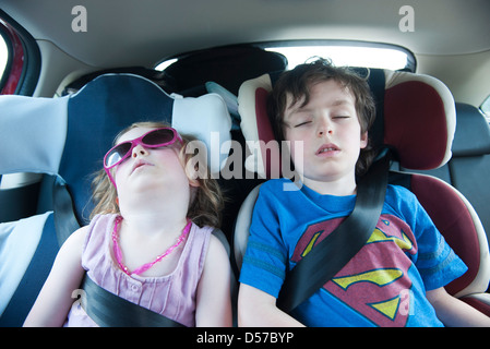 Boy and girl asleep in car seats Stock Photo