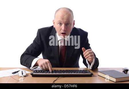 Surprised businessman sat at desk looking at computer screen isolated on white. Stock Photo
