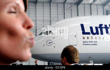 A woman poses next to the first Airbus A380 of German carrier Lufthansa at the airport of Frankfurt Main, Germany, 19 May 2010. The Airbus A380 was baptised on the name 'Frankfurt am Main', is 72 metres long, 15,000 kilometres range and can host up to 853 passengers. Lufthansa's new airplane will fly to Frankfurt Main with selected guests during the early afternoon to continue the  Stock Photo