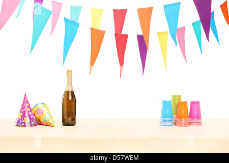 Bottle of sparkling wine, plastic glasses and party hats isolated on white background Stock Photo