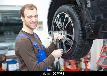 Mechanic changing the wheel on a car hydraulic lift Stock Photo