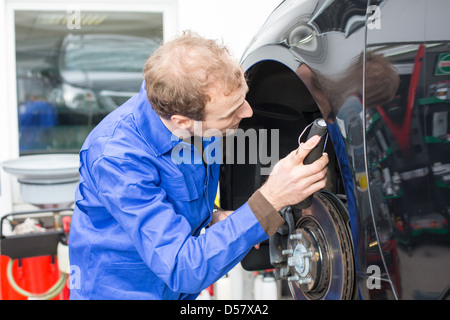 Car mechanic repairs the brakes of an automobile on a hydraulic lift Stock Photo