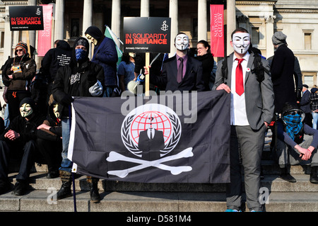 A group of protesters, some of them wearing anonymous masks at a rally in Trafalgar Square, London, UK.