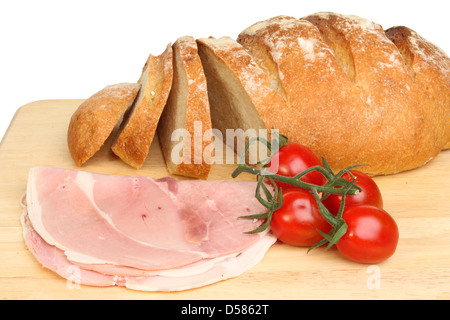 Freshly baked bloomer bread loaf with ham and tomatoes on a wooden board Stock Photo