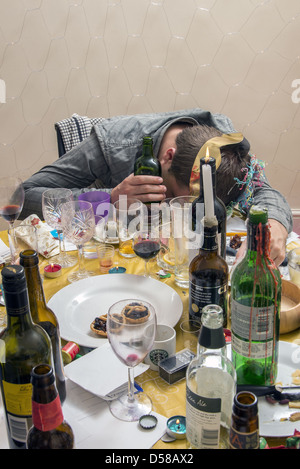 Man passed out at table with beer in hand at a Christmas party Stock Photo
