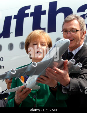 Smiling, German chancellor Angela Merkel (L)  holds a model of the Airbus A380 in her hands, which was presented to her by Lufthansa head Wolfgang Mayrhuber (R) during the International Aerospace Exhibition (ILA) at airport Berlin-Schoenefeld, Germany, 08 June 2010. The ILA is open in Germany's capitol until 13 June 2010. Photo: WOLFGANG KUMM Stock Photo