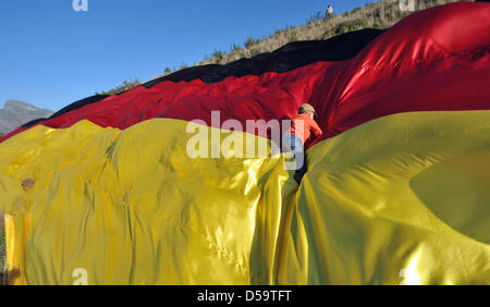 A young boy climbs across a huge German flag at the 'Signal Hill' in Cape Town, South Africa, 03 July 2010 shortly before the game 'Germany vs. Argentina' of the soccer World Cup 2010. Photo: Ralf Hirschberger Stock Photo