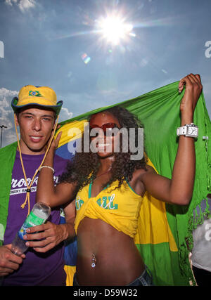 Brasilianische Fans schützen sich bei Temperaturen von über 30 Grad auf dem Fanfest in Hamburg am Freitag (02.07.2010) während des Viertelfinalspiels Niederlande-Brasilien mit einer Flagge gegen die Sonne. Die Holländer gewannen das Spiel mit 2:1. Foto: Bodo Marks dpa/lno