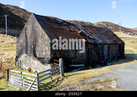 Derelict house with roof held down with fishing nets on the Uig road Isle of Lewis Western Isles Outer Hebrides Scotland UK Stock Photo