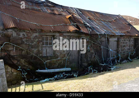 Derelict house with roof held down with fishing nets on the Uig road Isle of Lewis Western Isles Outer Hebrides Scotland UK Stock Photo