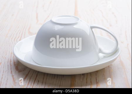 Cup upside down on a saucer, sitting on an old worn table. Stock Photo