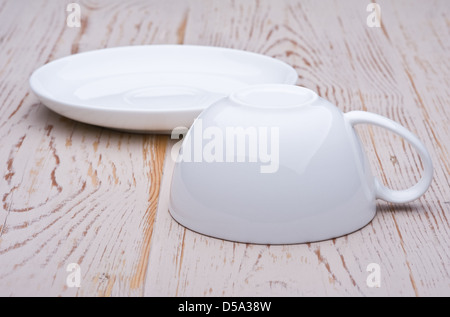Tea cup and saucer, standing separately on an old worn table. The cup upside down. Stock Photo