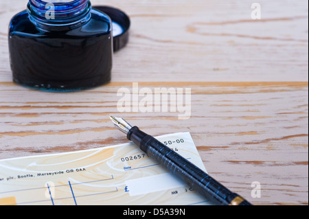 Cheque book, pen and bottle of ink. Stock Photo