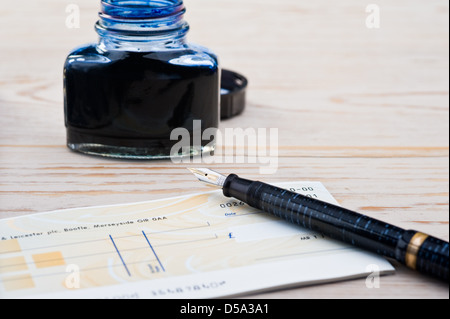 Cheque book, pen and bottle of ink. Stock Photo