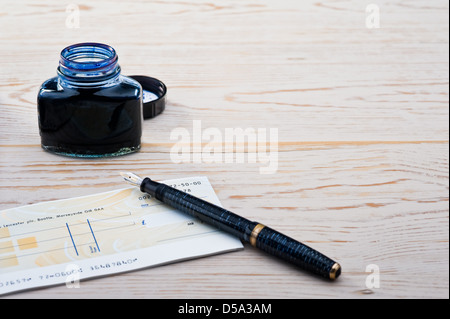 Cheque book, pen and bottle of ink. Stock Photo