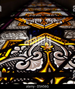 A tall stained glass window in a church, featuring mostly yellow and white glass. Stock Photo