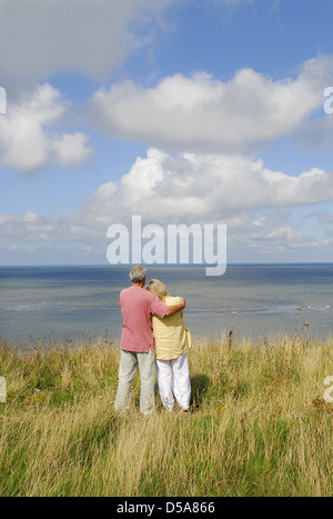 mature couple standing on cliff edge Stock Photo