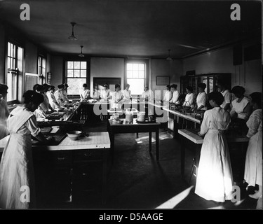 A photograph of the Foods Laboratory in the Home Economics Building at Cornell University, taken in October 1917. The instructor is seen working with students in a space dedicated to food and nutrition studies. This building is now known as Comstock Hall. Stock Photo