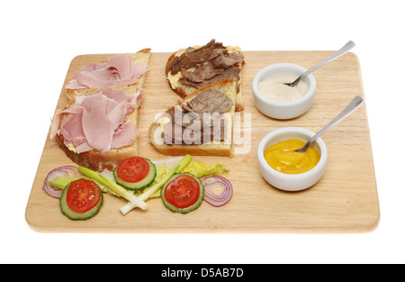 Beef and ham open sandwiches with salad, mustard and horseradish sauce on a wooden board isolated against white Stock Photo