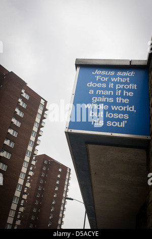 'Jesus said' Biblical quotations on a city church and bleak background tower blocks in the London borough of Southwark. Locals in these bleak south London streets may be uplifted by the words from the Christian scriptures, comforting the troubled with messages of humanity from the Bible, perhaps guiding Londoners incarcerated in the depressing 1960s tower block high-rises, homes to the poor and the dispossessed. Stock Photo