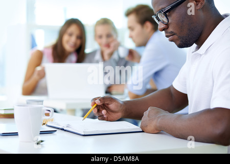 Concentrated young man in the foreground planning his workday Stock Photo