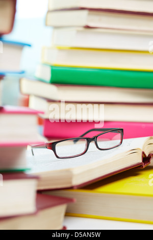 Vertical image of eyeglasses lying over opened book in the library Stock Photo