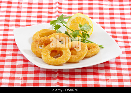 deep fried breaded calamari(squid) rings served in a white plate on a traditional napkin Stock Photo