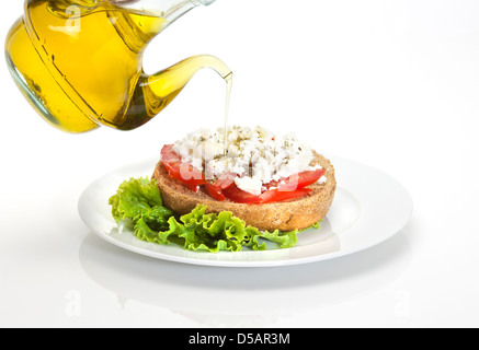 typical Cretan plate called ntakos, a slice of barley bread , cubes of tmato, goat cheese, virgin olive oil and herbs Stock Photo