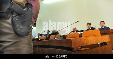 The two defendants Markus S. (R, dark shirt) and Sebastian L. (L, white shirt), sit among their defense lawyers (C) under the watchful eye of an armed judicial officer at the begin of their trial at the Regional Court in Munich, Germany, 13 July 2010. Ten months after the murder of manager Dominik Brunner, the trial of two young men has begun. Sebastian, 17 years at the time of the Stock Photo
