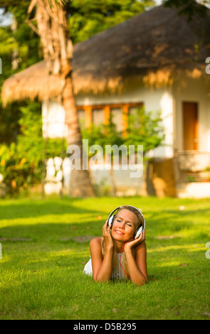 Beautiful emotional girl with headphones enjoying nature and music at sunny day. Stock Photo