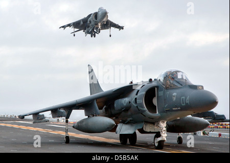 A US Marine Corps AV-8B Harrier II jet fighter aircraft lands while another waits on the flight deck of the amphibious assault ship USS Boxer March 26, 2013 off the coast of Southern California. Stock Photo