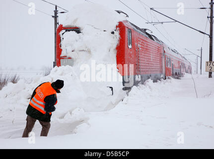 An officer of the German Federal Police examines a train which is stuck in snow on the track between Stralsund and Berlin near Anklam, Germany, 11 January 2010. The rescue work of the train which got stuck in snow on 10 January shall be initiated in the course of the day and last until late afternoon. Snow drifts continue to obstruct the train and road traffic throughout Mecklenbur Stock Photo