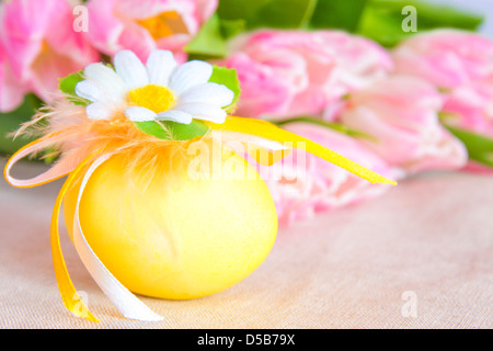 Decorated Easter egg with pink tulips over linen background. Stock Photo