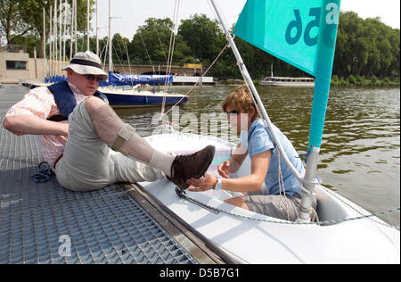 Physiotherapist Christina Groll (R) helps hemiplegic Klaus out of the boat 'Access Dinghi' that was designed for handicapped persons on the Aasee near Muenster, Germany, 01 July 2010. Germany's only sailing therapy school 'physiosail' offers sailing therapy for the handicapped. Photo: Friso Gentsch Stock Photo