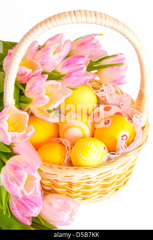 Easter concept. Basket painted Easter eggs and pink tulips isolated on white background. Stock Photo