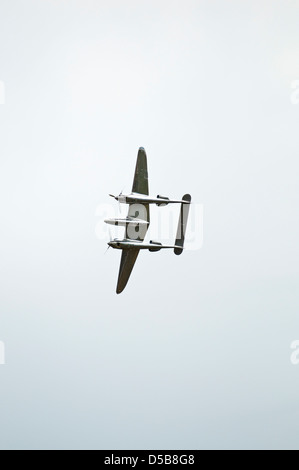 Portrait image of a World war two vintage fighter plane flying over head, isolated against a grey sky. Stock Photo