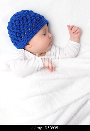 Beautiful baby sleeping on bed under a white blanket Stock Photo