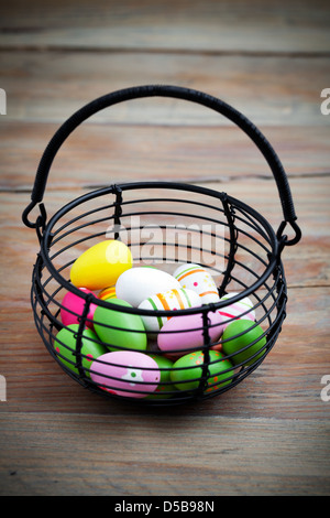 Colorful easter eggs in black wire basket Stock Photo