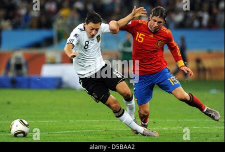 Germany international Mesut Ozil (L) and Spain international Sergio Ramos (R) vie for the ball during 2010 FIFA World Cup semi-final match Germany vs Spain in Durban, South Africa, 07 July 2010. On 17 August 2010, Oezil's club Werder Bremen confirmed that Germany midfielder Mesut Oezil will move from the Bundesliga club to Real Madrid. Bremen refused to state what size transfer fee Stock Photo