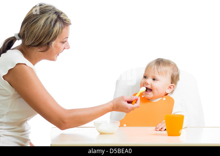 mom feeding her happy baby girl by spoon Stock Photo