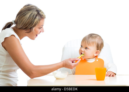 young mom feeding her happy baby girl with help of spoon Stock Photo