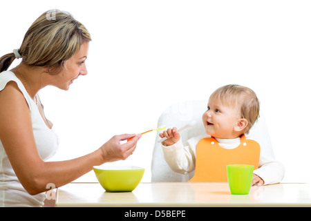 young mother spoon feeding her cute baby girl isolated on white Stock Photo