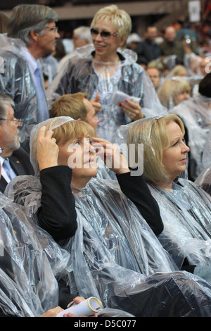 Norbert Lammert Bettina Wulff Angela Merkel celebrating the Mass of Pope Benedict XVI at olympic stadium wearing rain coats. Stock Photo